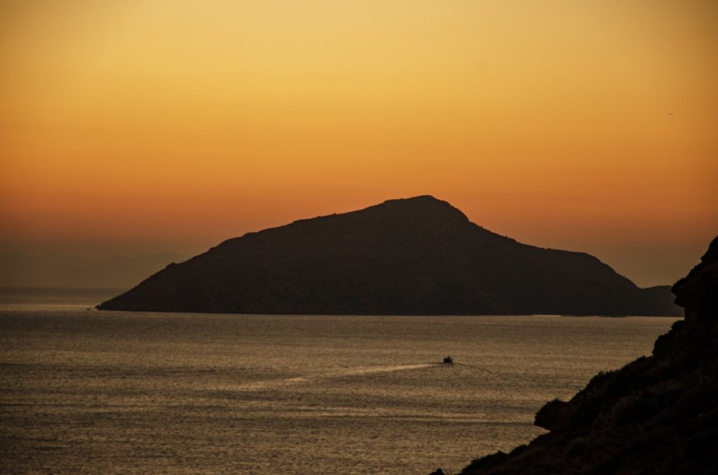 patrikos island with sunset colours in the sky behind and small boat in the sea