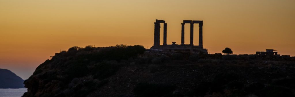Temple Of Poseidon silhouetted against sun-setting coloured sky