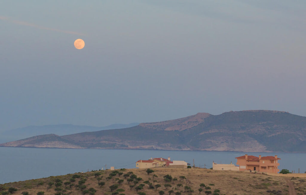 full moon rising above island of makronisos