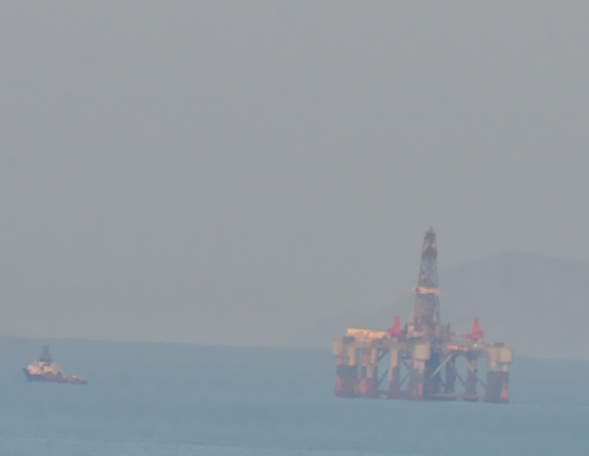 drilling platform being pulled by tug boat near Island of Kea